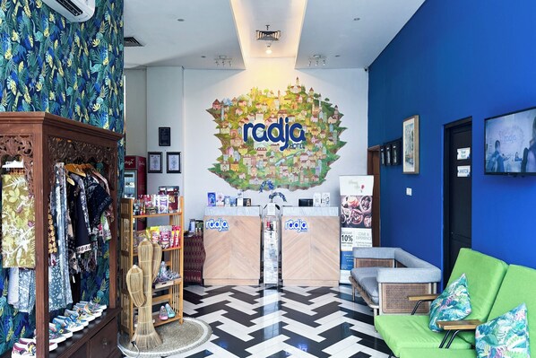 A reception area with a 'radja hotel' sign, a reception desk, a green sofa, and a patterned wall. - Radja Art and Boutique Hotel Simpang Lima (Semarang)