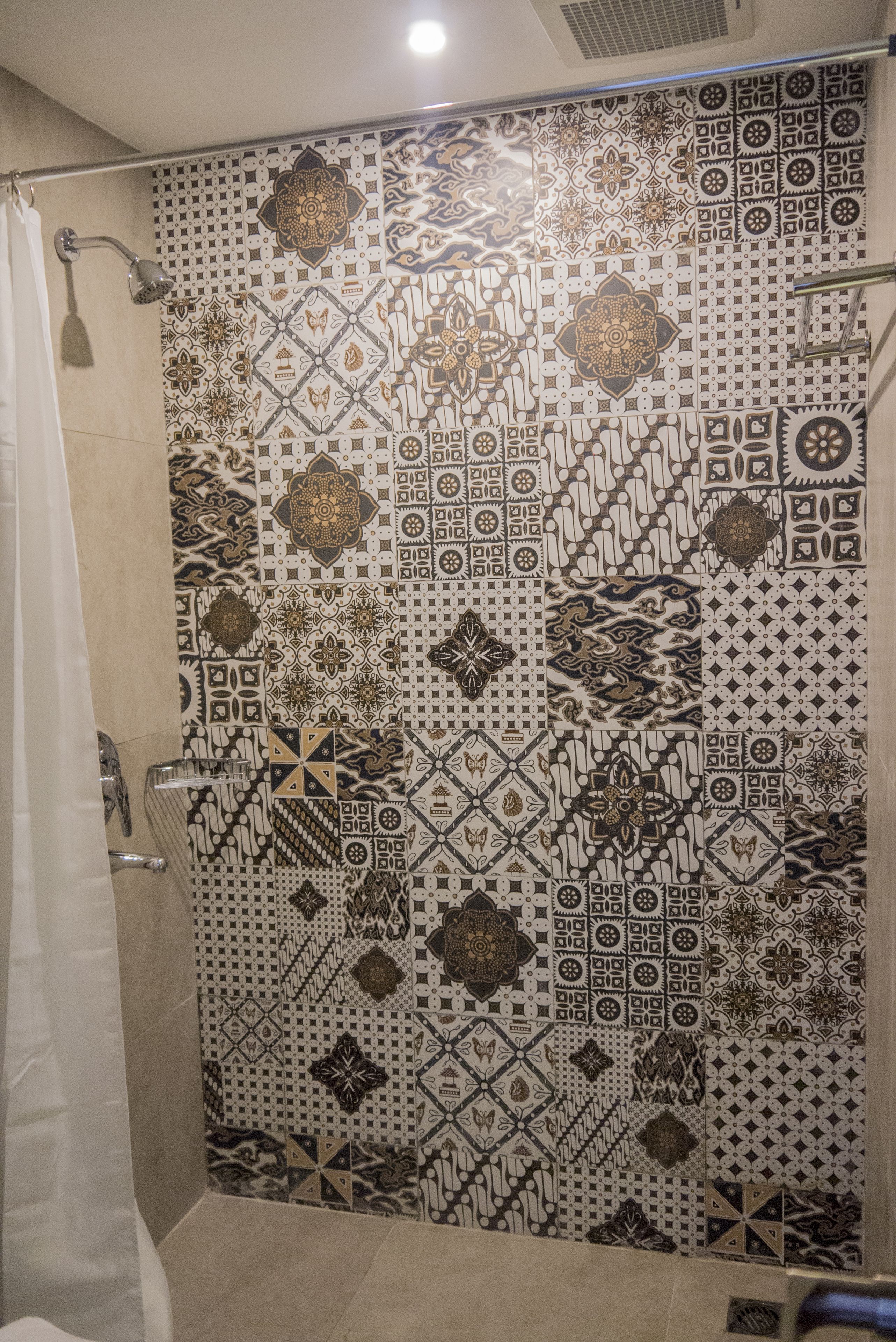 Una ducha con pared de azulejos estampados y cortina.