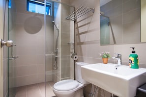 A bathroom with a glass shower enclosure, a toilet, a sink with a mirror, and a potted plant. - A4 COZY Atlantis Family Suites 4-6pax-Pool View-Jonker (Malacca City)
