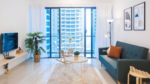 A modern living room with a sofa, TV, and a dining table with chairs. - A4 COZY Atlantis Family Suites 4-6pax-Pool View-Jonker (Malacca City)