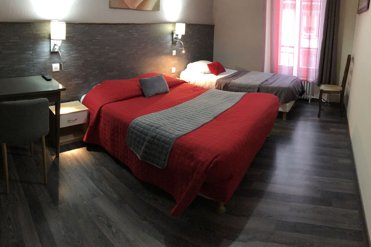 Una camera d'albergo con due letti, una scrivania e una sedia.