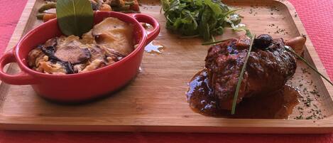 A meal with a red bowl, a steak, and greens on a wooden board.