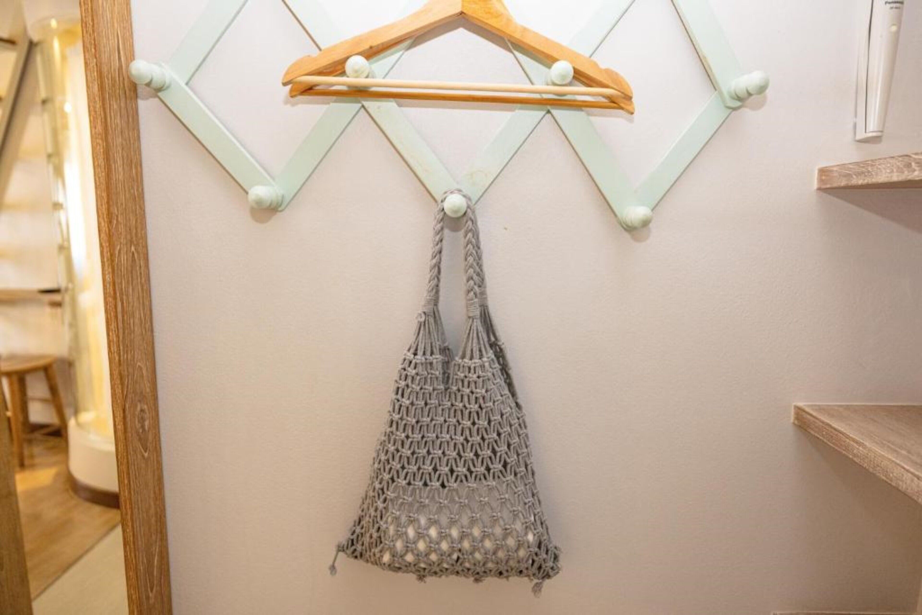 Un perchero de pared con un colgador de madera y un bolso de macramé.