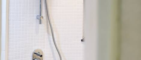 A shower with a handheld showerhead and a wall-mounted control panel.
