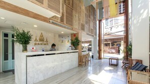 Un espace d’accueil moderne avec un comptoir en marbre, des éléments décoratifs en bois et une vue sur un espace extérieur aménagé pour s’asseoir.