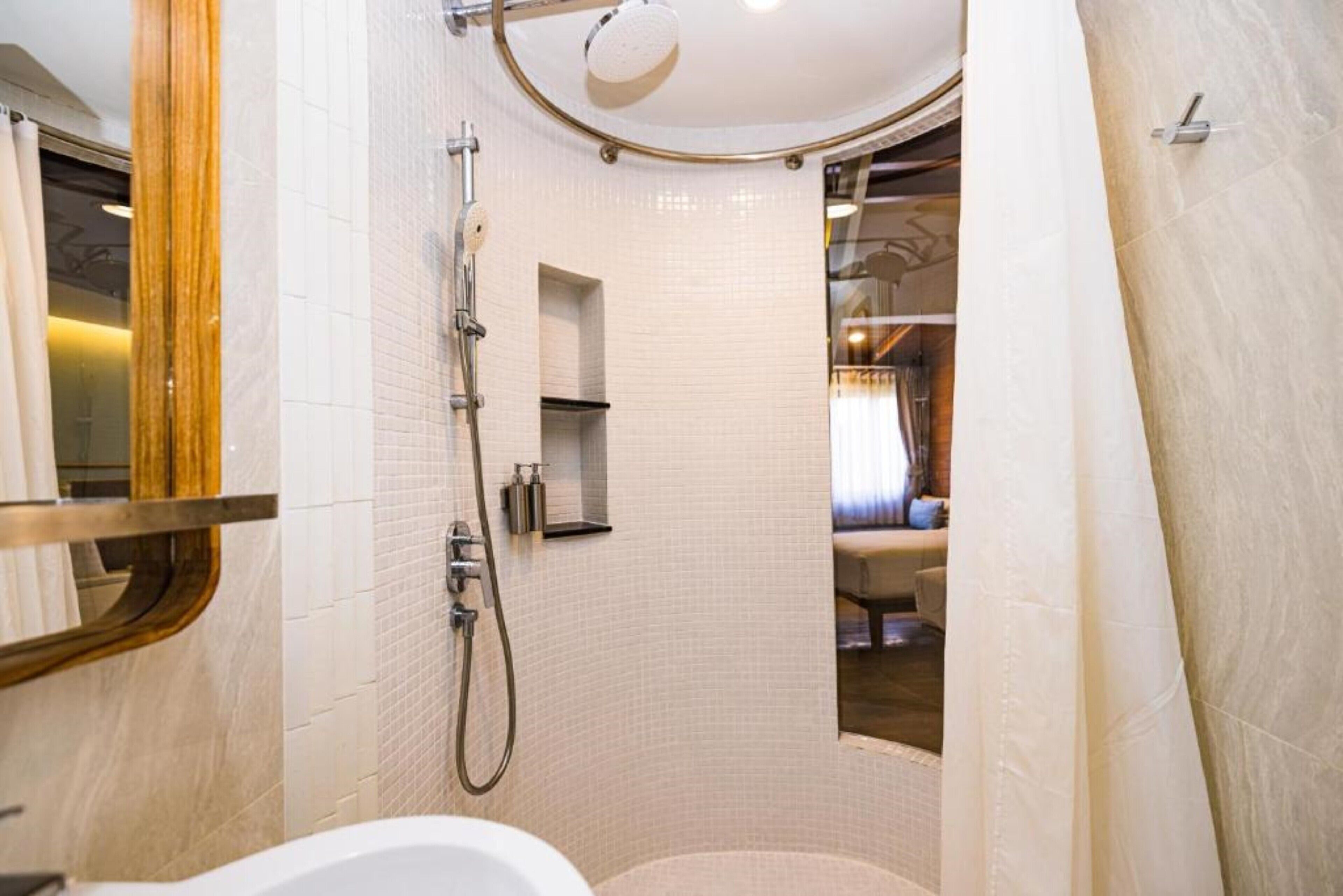 A modern bathroom with a curved shower, a vanity with a mirror, and a bathtub.
