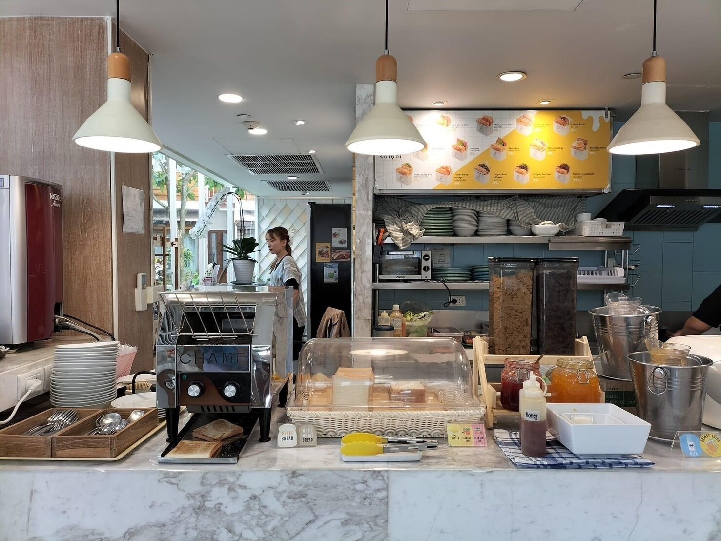 Un mostrador de panadería con una exhibición de pan, una máquina de café y diversas herramientas de repostería.