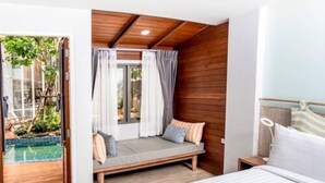 Une chambre avec un plafond en bois, un lit, une table de chevet et une fenêtre avec des rideaux.