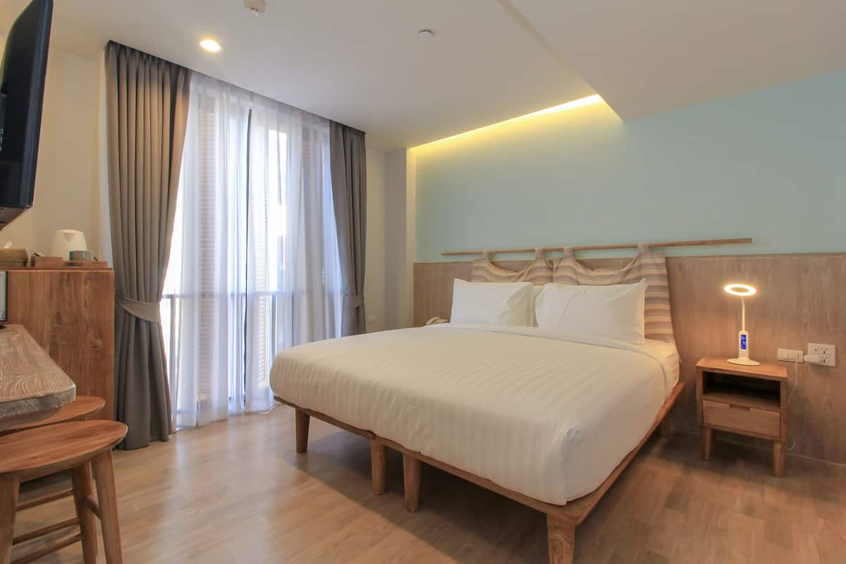 Une chambre d’hôtel bien aménagée, avec un grand lit, des tables de chevet, une télévision et une fenêtre avec des rideaux.