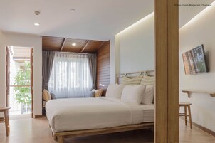 Une chambre à coucher comprenant un lit, une table de chevet, une chaise, une fenêtre avec des rideaux et une plante visible à travers la fenêtre.