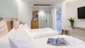Une chambre d’hôtel avec deux lits, une télévision, une petite table et une salle de bain visible à travers une porte ouverte.