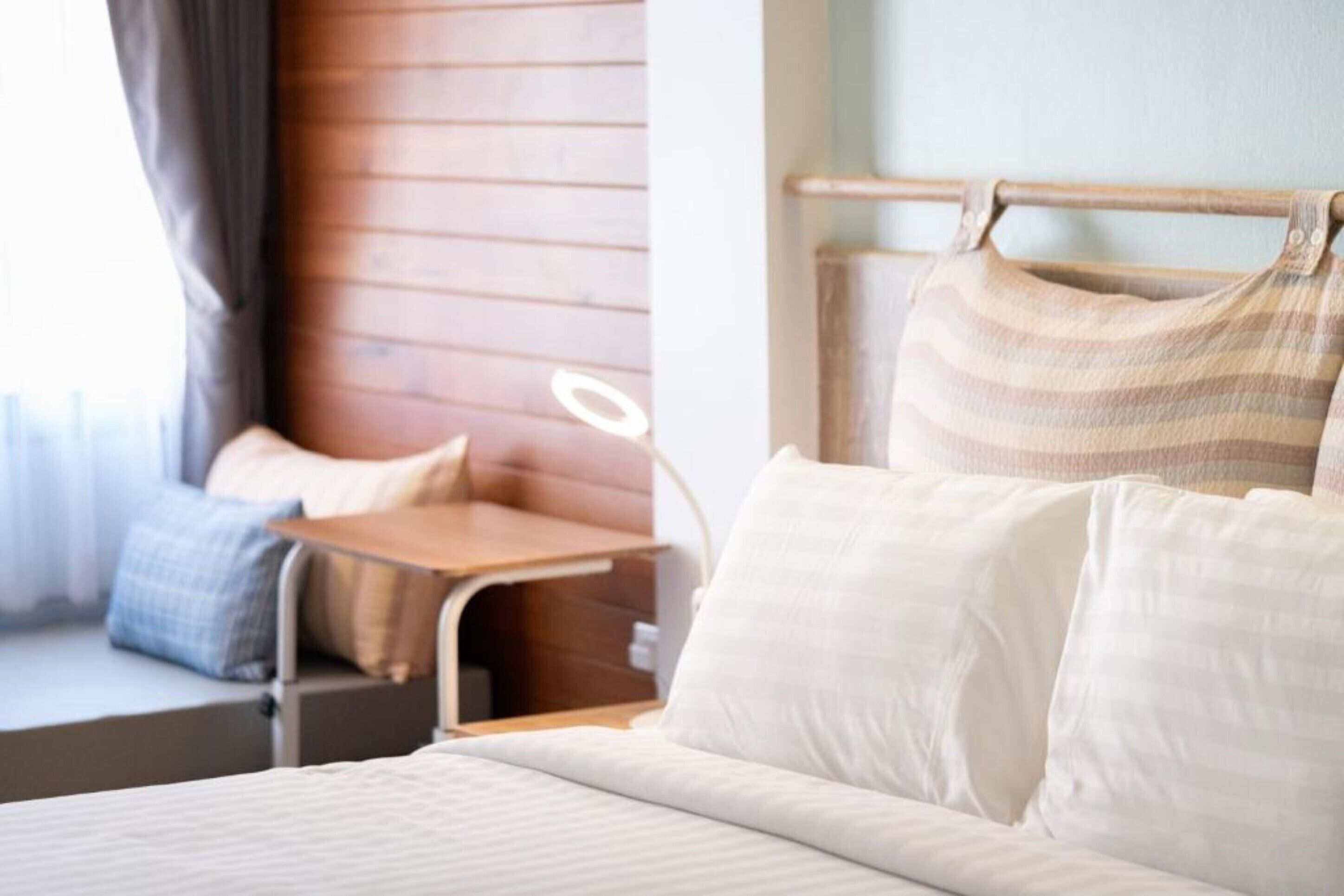 Una habitación de hotel con cama, mesita de noche y ventana con cortinas.