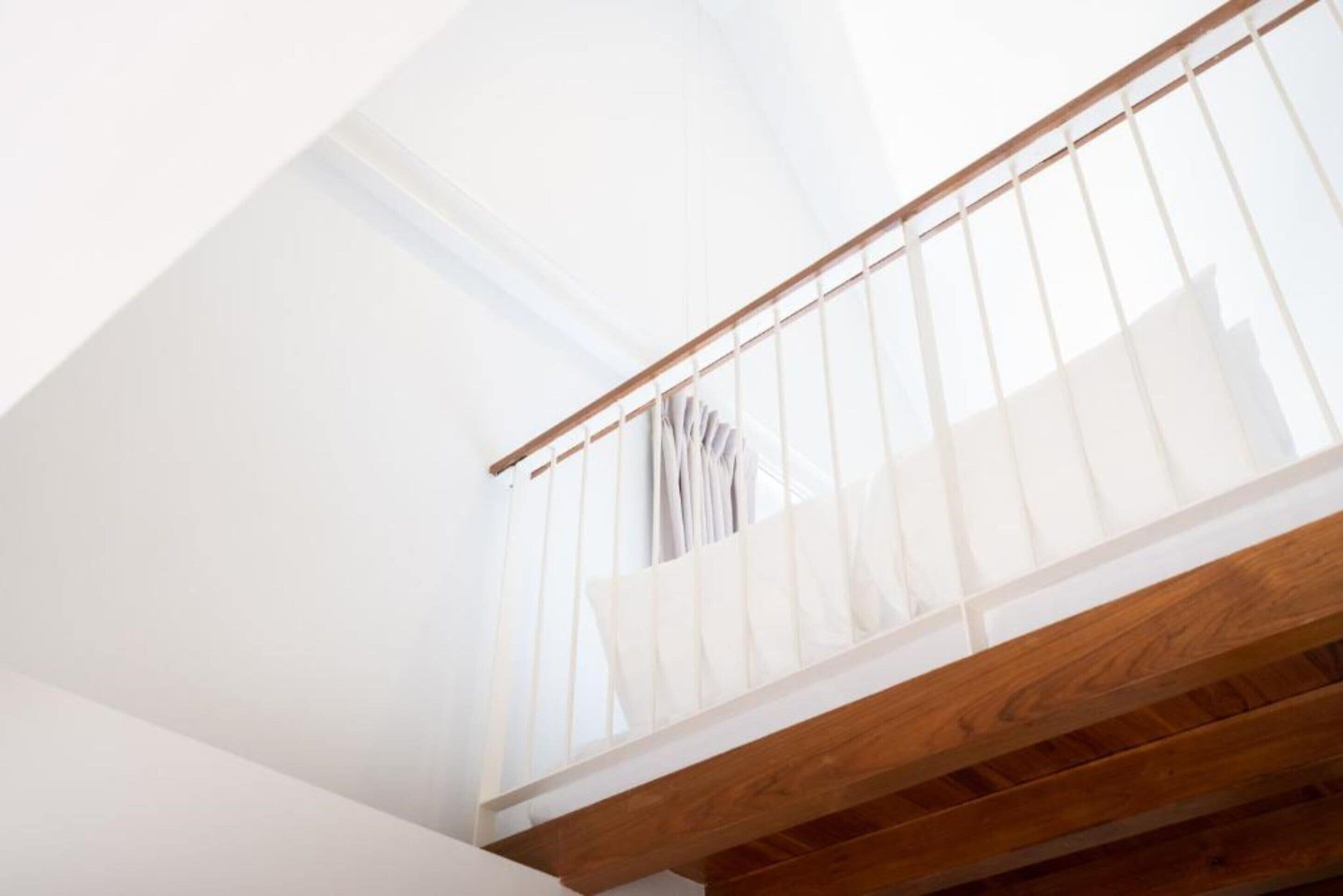A wooden staircase with a white railing and a view of a building outside.