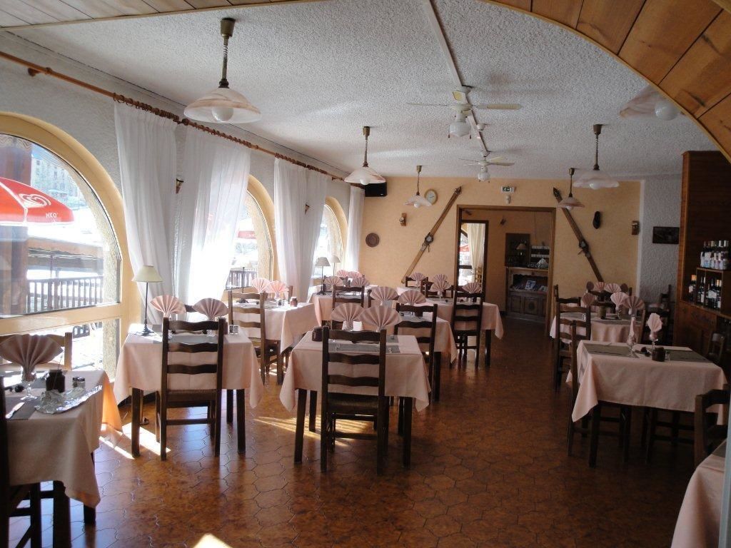 Ein Restaurant mit mehreren Tischen und Stühlen, einem gefliesten Boden und einer gewölbten Decke mit hängenden Lampen.