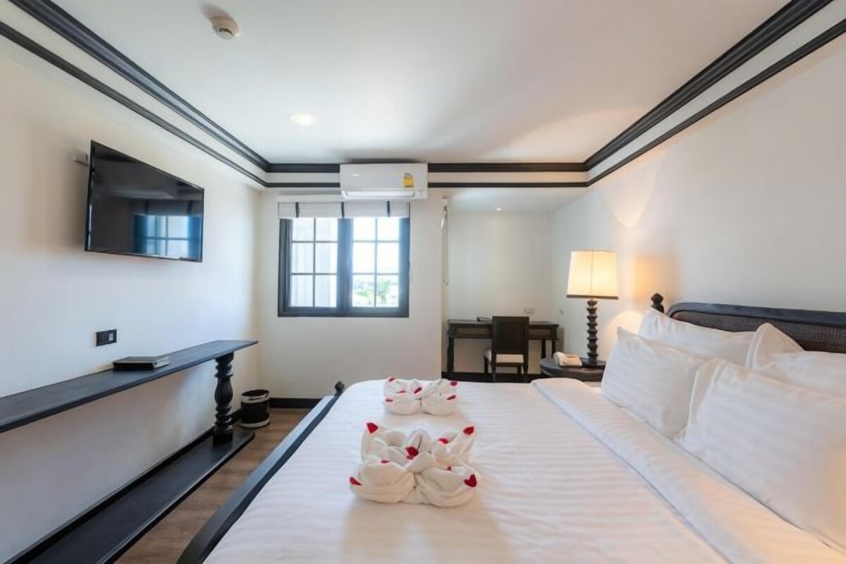 A hotel room with a large bed, a flat-screen TV mounted on the wall, a desk, and a chair.