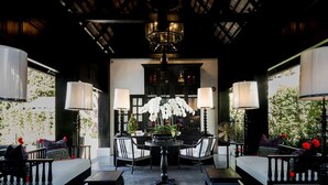 A dining area with a central table surrounded by chairs, a chandelier, and potted plants. - MORA Boutique Hotel (Chiang Rai)