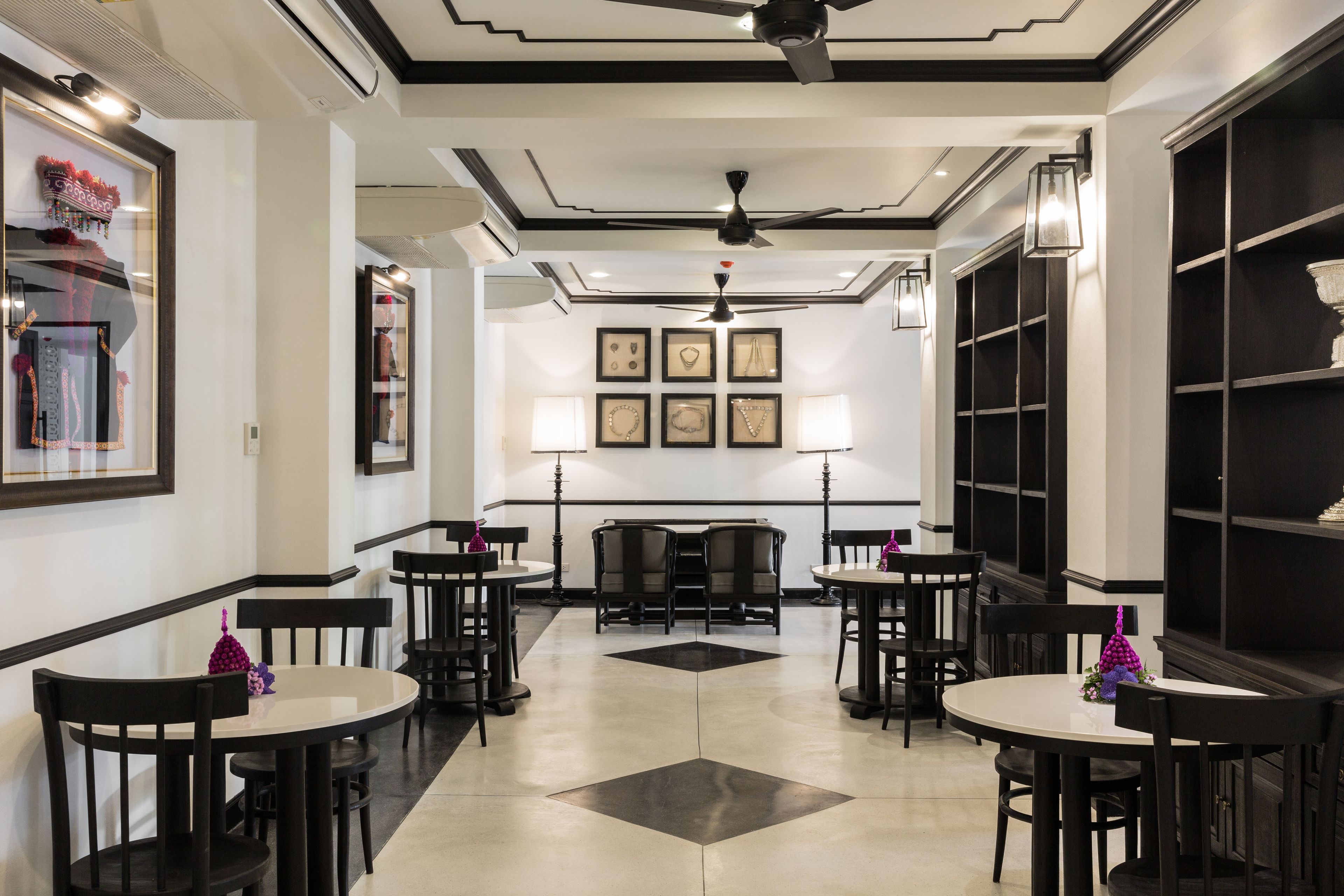 A hotel lobby with black and white decor, multiple tables and chairs, and framed pictures on the walls.