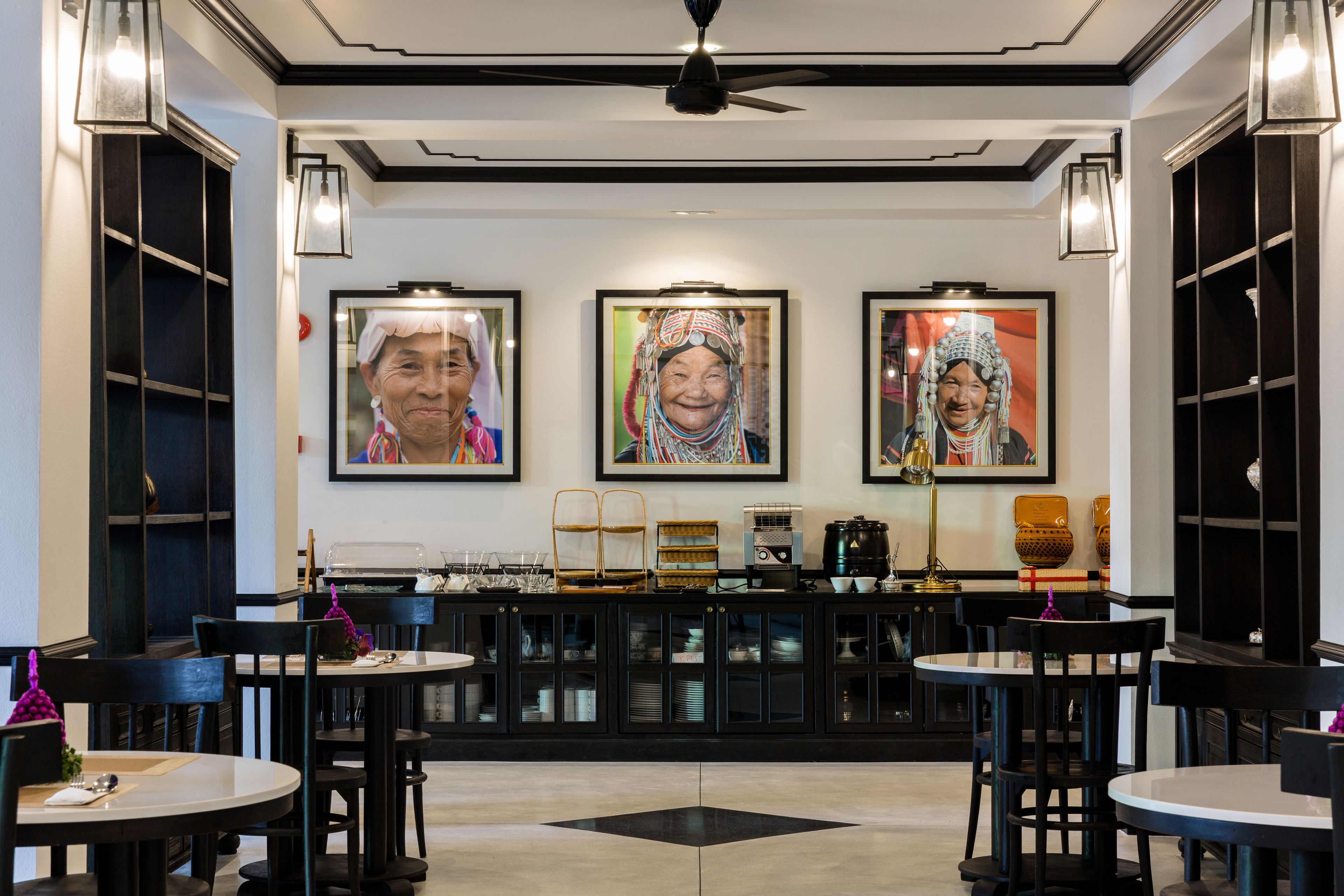 Un restaurant avec des tables et des chaises, un comptoir avec une machine à café et des tableaux encadrés accrochés au mur.