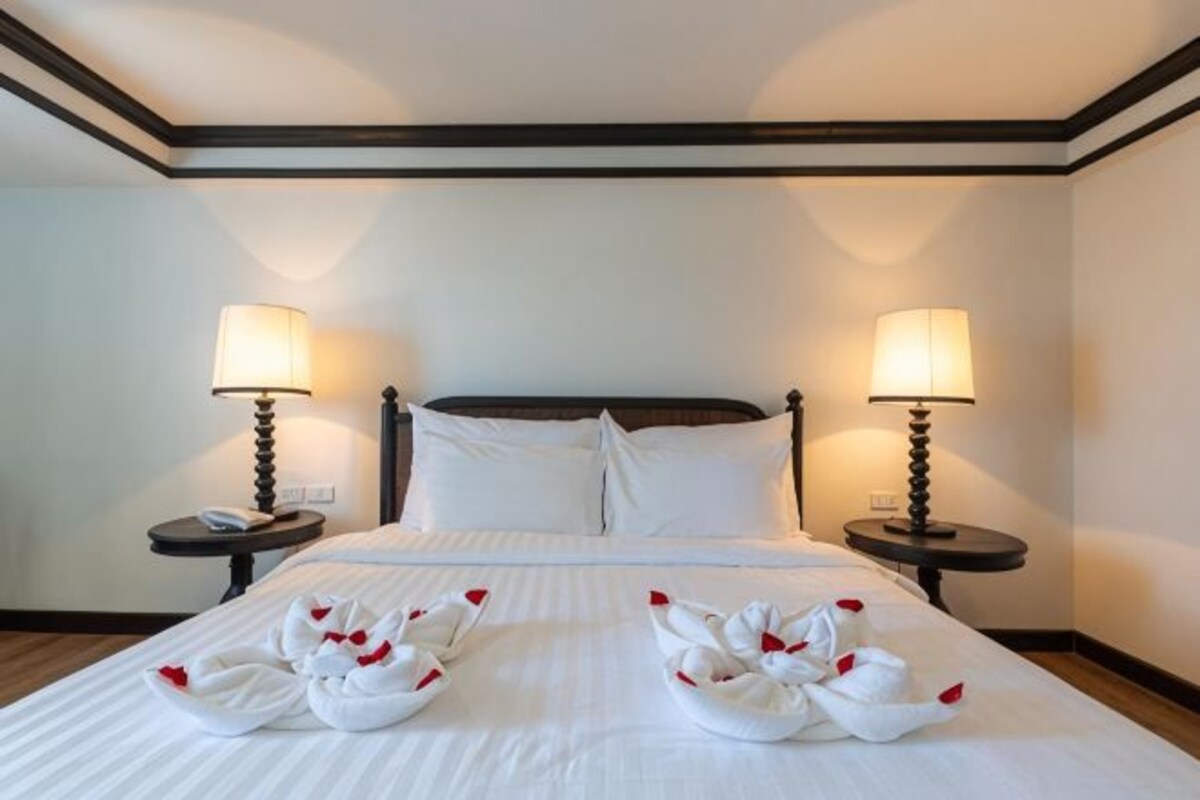 Een hotelkamer met een groot bed, twee nachtkastjes met lampen en een hoofdeinde.