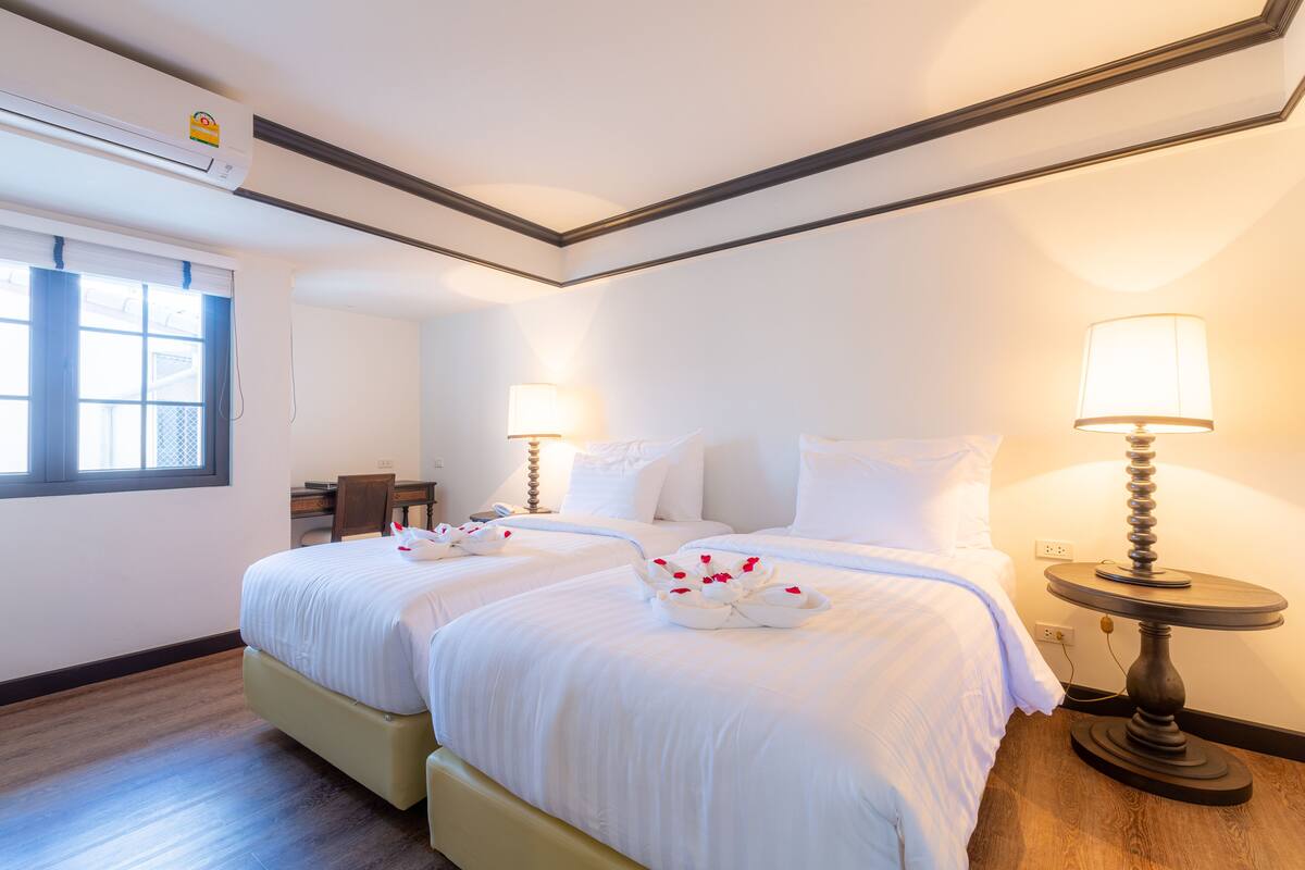 Habitación de hotel con dos camas, un escritorio y una lámpara.