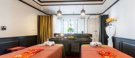 A hotel room with two beds, a small desk, a mirror, and a window with curtains.