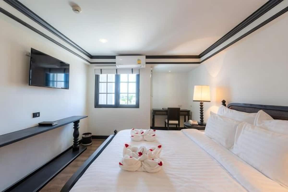Una habitación de hotel con una cama grande, un televisor de pantalla plana en la pared, un escritorio y una silla.