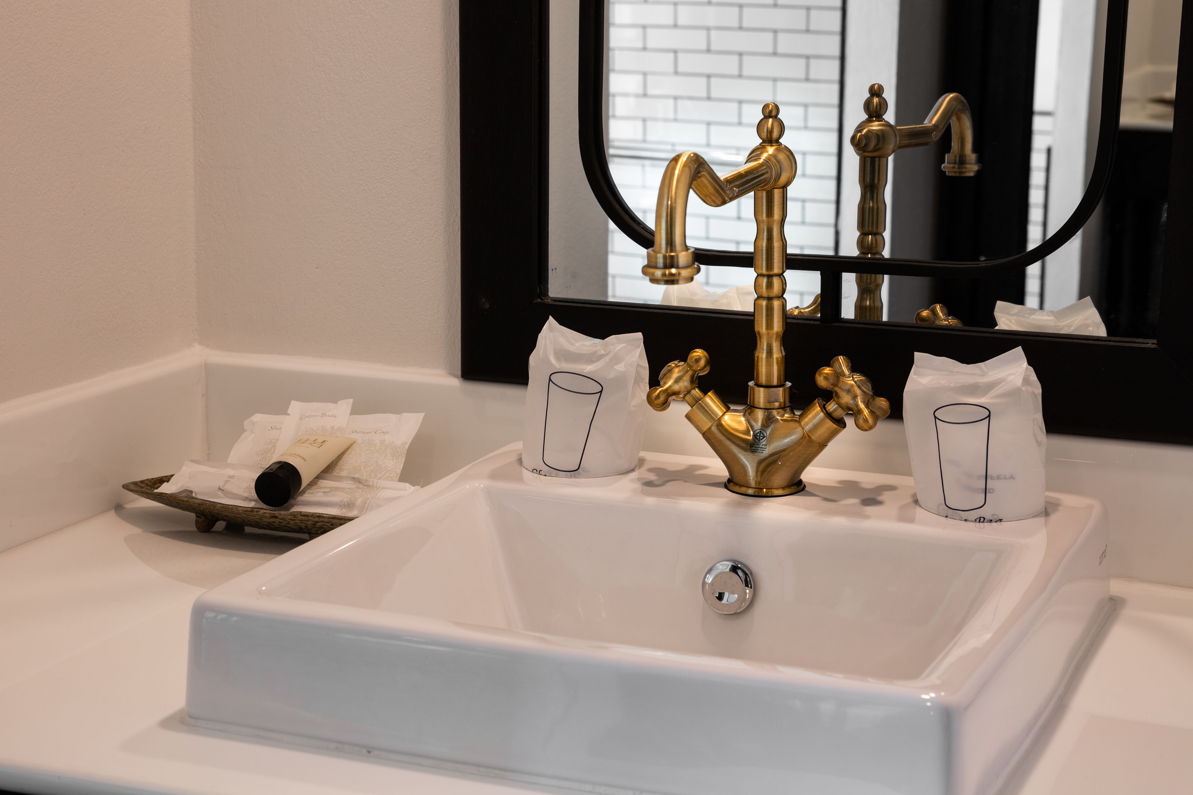 Une salle de bain avec un lavabo blanc, un robinet doré et un miroir au-dessus.