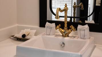 Un baño con un lavamanos blanco, un grifo dorado y un espejo encima.