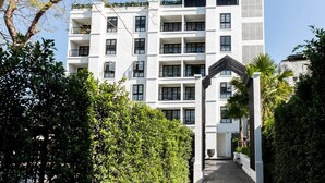 A multi-story hotel with a central courtyard, surrounded by lush greenery and a clear sky. - MORA Boutique Hotel (Chiang Rai)