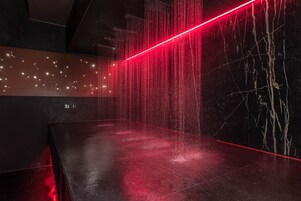 Un interno moderno con pavimento scuro, una striscia di luce rossa e una parete dalla texture simile al marmo.