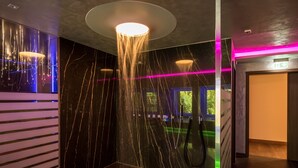 Ein modernes Badezimmer mit Marmorwand, einer Pendelleuchte und einer Duschkabine.