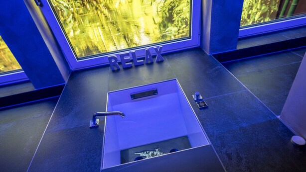 Ein modernes Badezimmer mit einem großen Fenster, einem Waschbecken und dem Wort "RELAX" auf dem Boden.