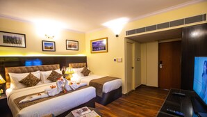 A hotel room with two beds, a television, and a newspaper on the table. - Hotel Paramos Inn (Bengaluru)