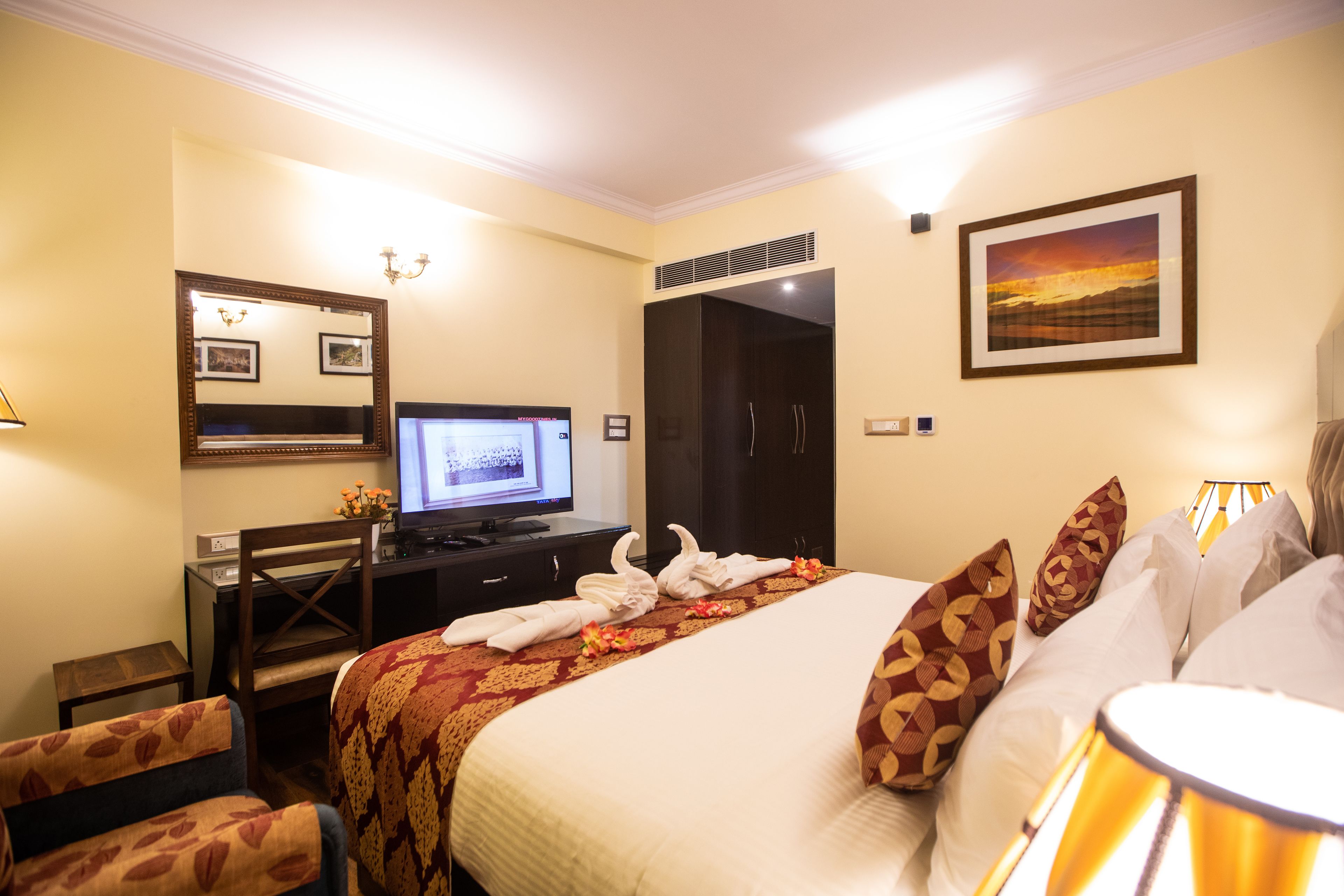 Habitación de hotel con cama, escritorio con computadora, armario y un cuadro en la pared.