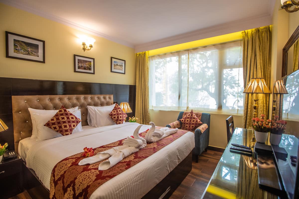Quarto de hotel com uma cama grande, uma mesa de jantar e vista para o exterior.