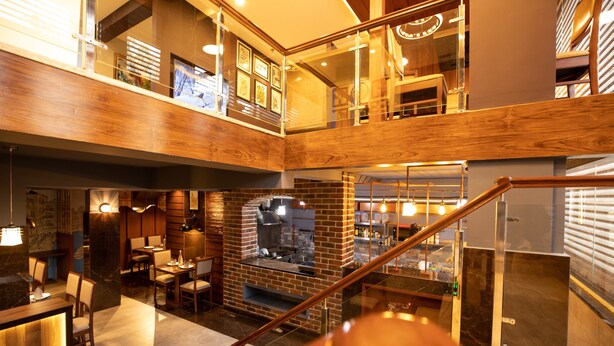 A multi-level interior with a dining area, kitchen, and seating. - Hotel Paramos Inn (Bengaluru)
