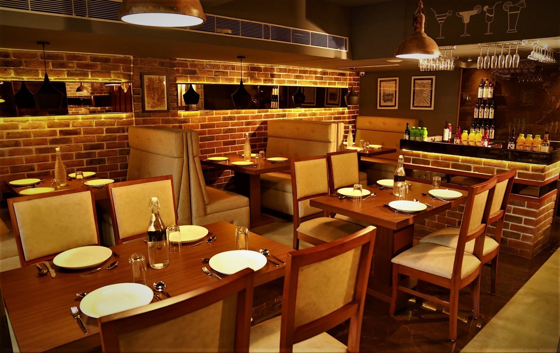 Un restaurante con paredes de ladrillo, mesas y sillas de madera. Hay botellas y vasos en la barra.
