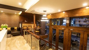 A modern hotel lobby with a reception desk, seating area, and a staircase leading to a second floor. - Hotel Paramos Inn (Bengaluru)