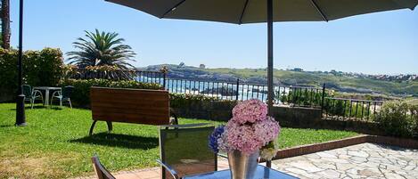 An outdoor patio with a table, chairs, a bench, and a large umbrella.