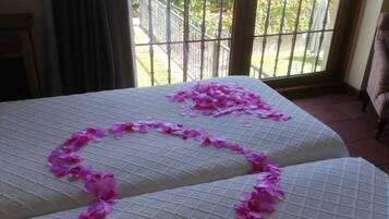 Une chambre avec un lit décoré de pétales de fleurs roses disposées en forme de cœur.