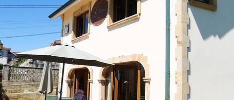 A two-story building with a balcony, a bench in front, and a sign indicating a restaurant.