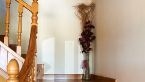 Eine Holztreppe mit Geländer, die zu einer Zwischenebene mit einem Blumenstrauß führt.