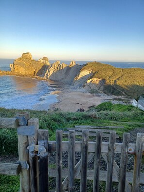 A coastal landscape with rocky cliffs and a sandy beach. - La Venta Del Mar (Pielagos)
