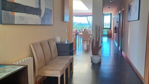 A spacious hallway with a modern aesthetic, featuring a sofa, a dining area, and a large abstract painting on the wall. - La Venta Del Mar (Pielagos)