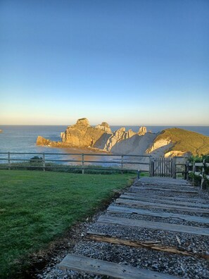 A pathway leading to a coastal area with rocky formations and a clear view of the sea. - La Venta Del Mar (Pielagos)