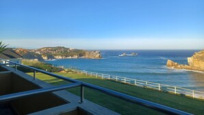 A coastal view from a balcony with a railing, overlooking the sea and a distant town. - La Venta Del Mar (Pielagos)