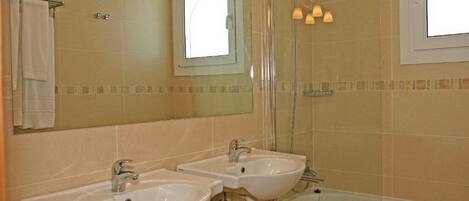 Une salle de bain avec deux lavabos, une douche et une baignoire.