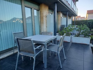 Eine Terrasse im Freien mit Tisch und Stühlen, einer kleinen Sitzecke und Blumentöpfen.
