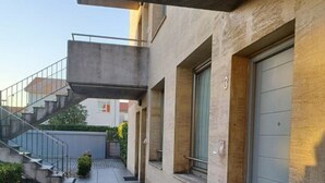 Un bâtiment moderne doté d’une passerelle couverte, d’un escalier et d’une porte portant le numéro 3.