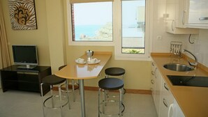 Une cuisine compacte avec un coin repas, un téléviseur et une vue sur la mer.